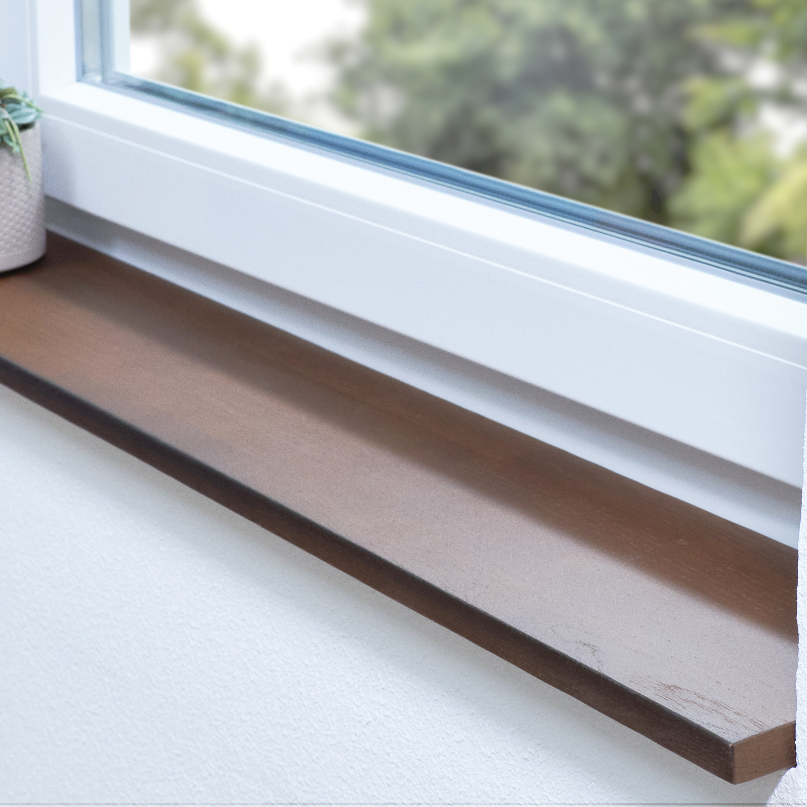 Appui de fenêtre en chêne teinté brun, abouté, dans une embrasure blanche avec plante en pot et vue sur la verdure