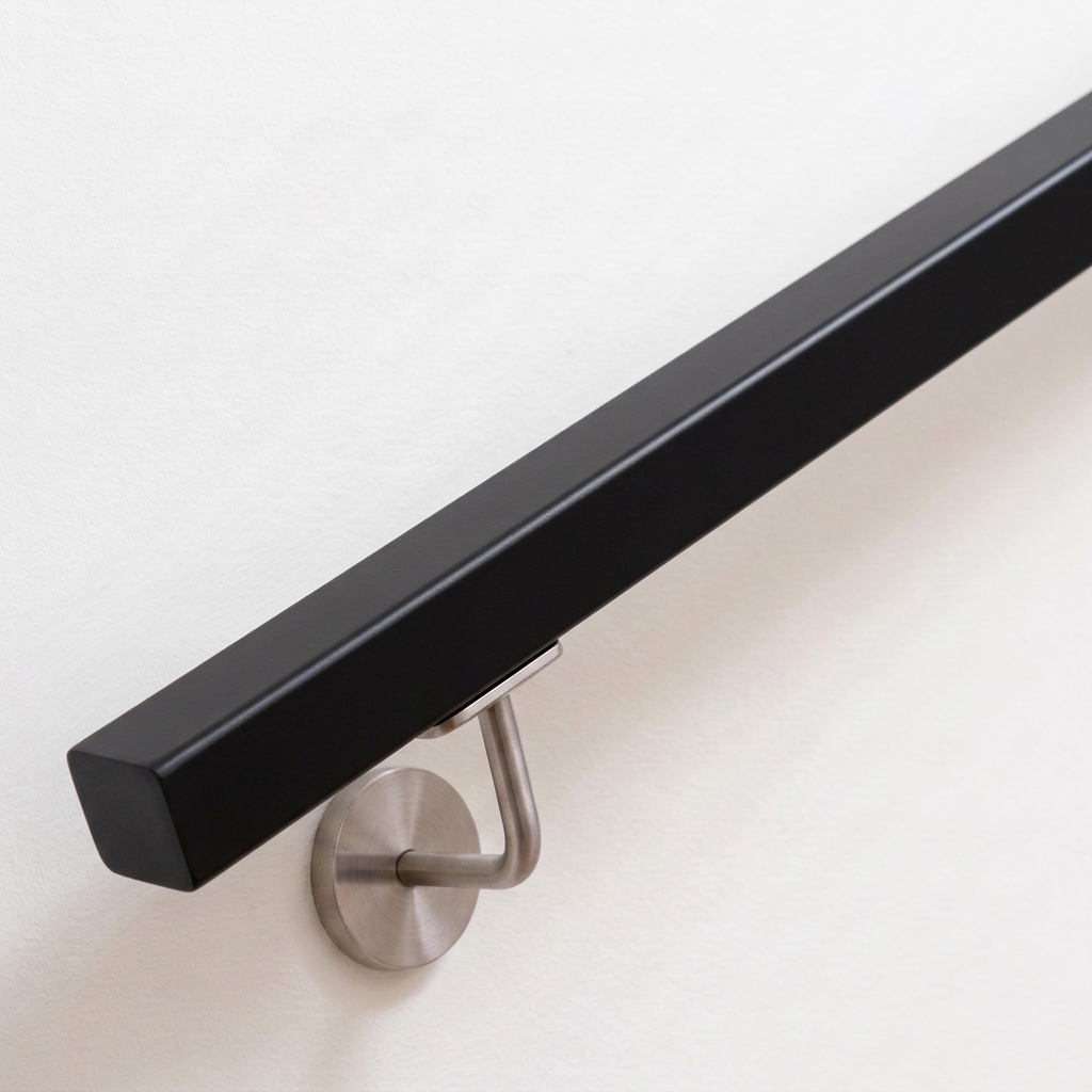 Main courante carrée en hêtre laquée noir avec support inox sur mur blanc, extrémité droite, vue oblique de dessus