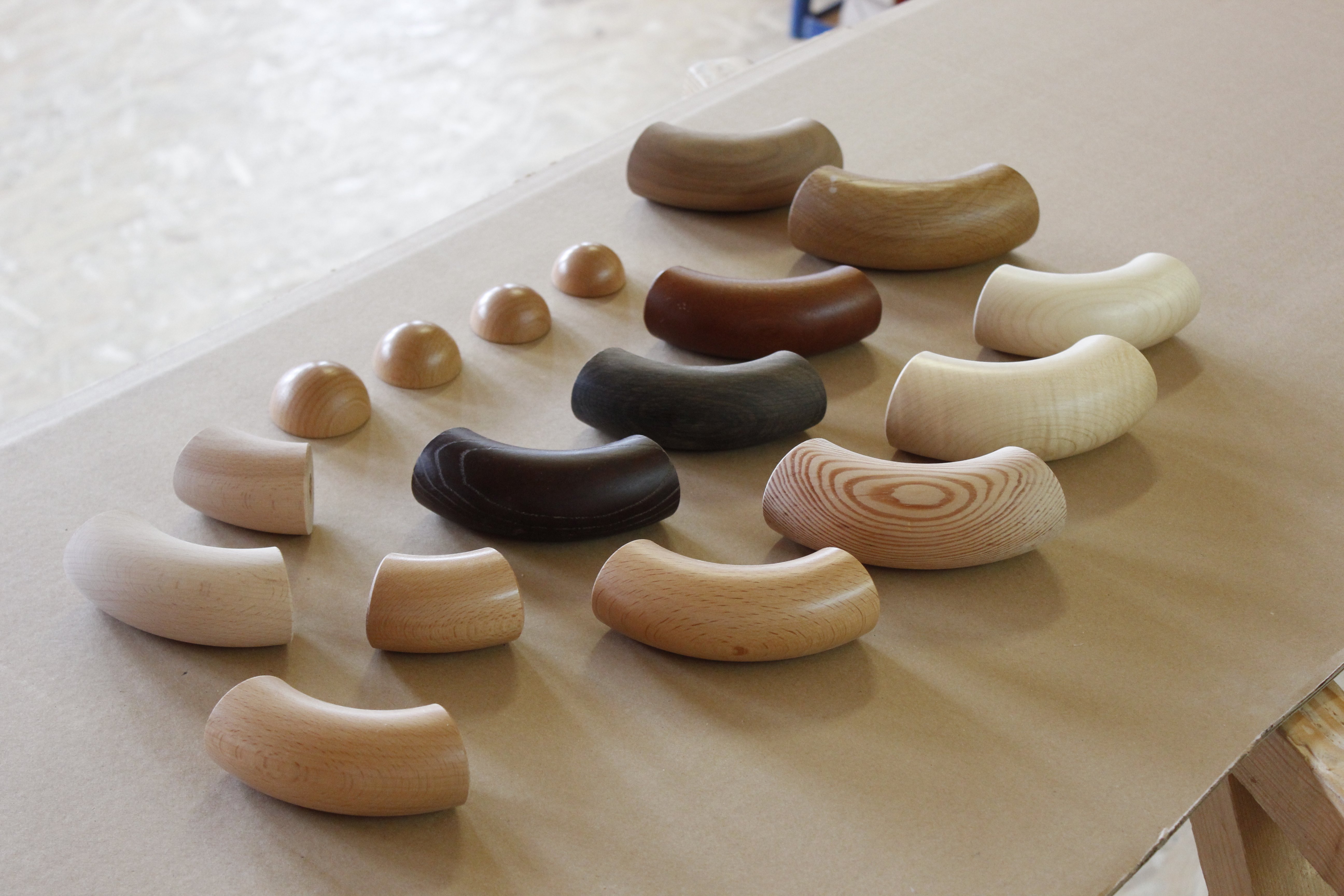 Accessoires de main courante en bois : coudes et embouts demi-ronds en différentes essences sur papier à l'atelier