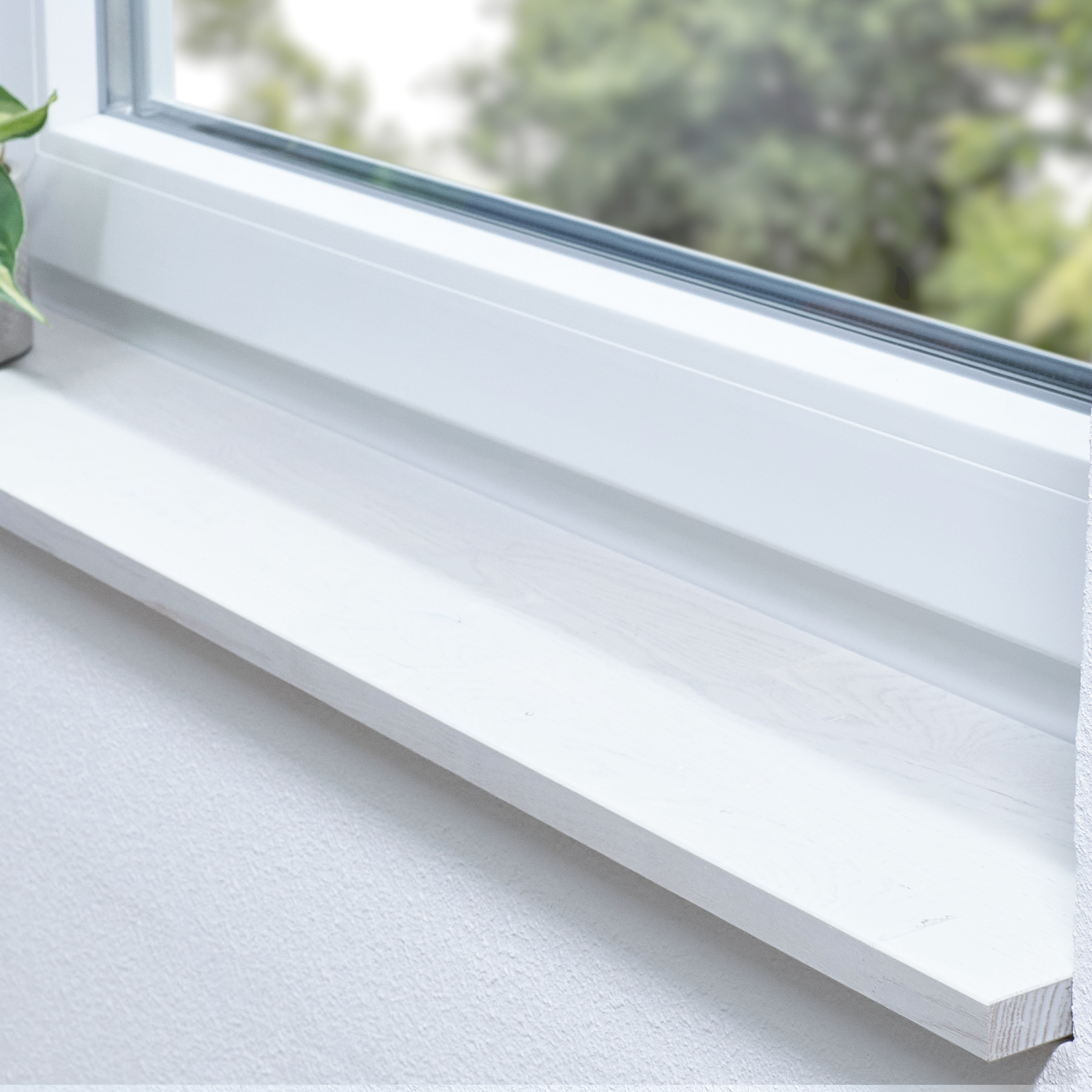 Appui de fenêtre en chêne sauvage teinté blanc, abouté, dans une embrasure blanche avec plante et vue sur la verdure