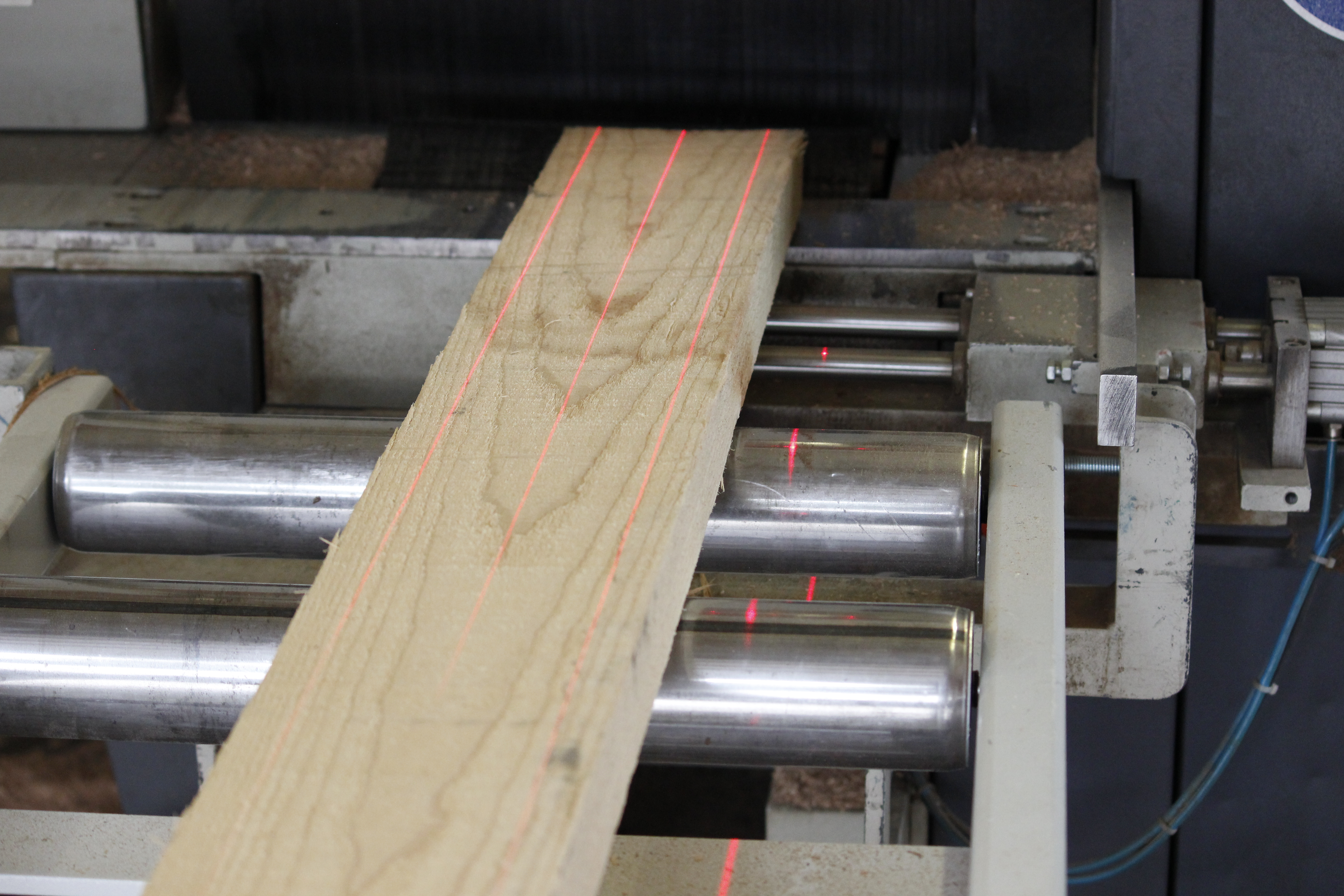 Madrier en bois sur rouleaux de machine avec lignes laser rouges, découpe précise dans la fabrication d'appuis de fenêtre