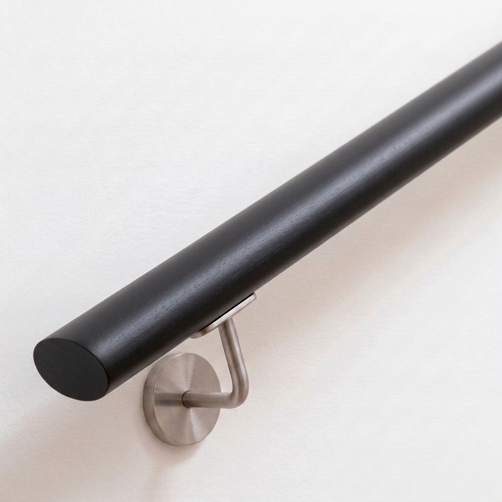 Main courante ovale en hêtre laquée noir avec support inox sur mur blanc, extrémité droite, vue oblique de dessus