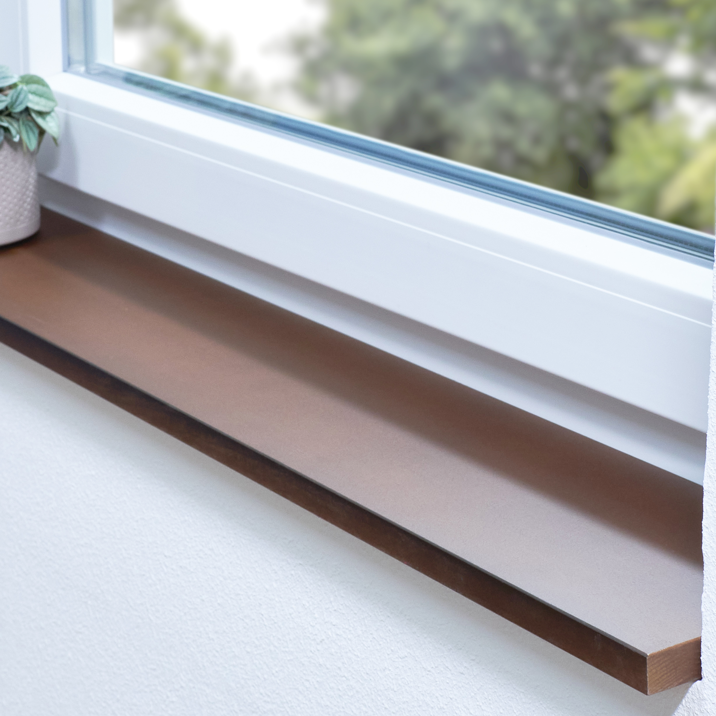 Appui de fenêtre en hêtre teinté brun abouté sur mesure, posé dans une niche devant une fenêtre blanche avec plante verte