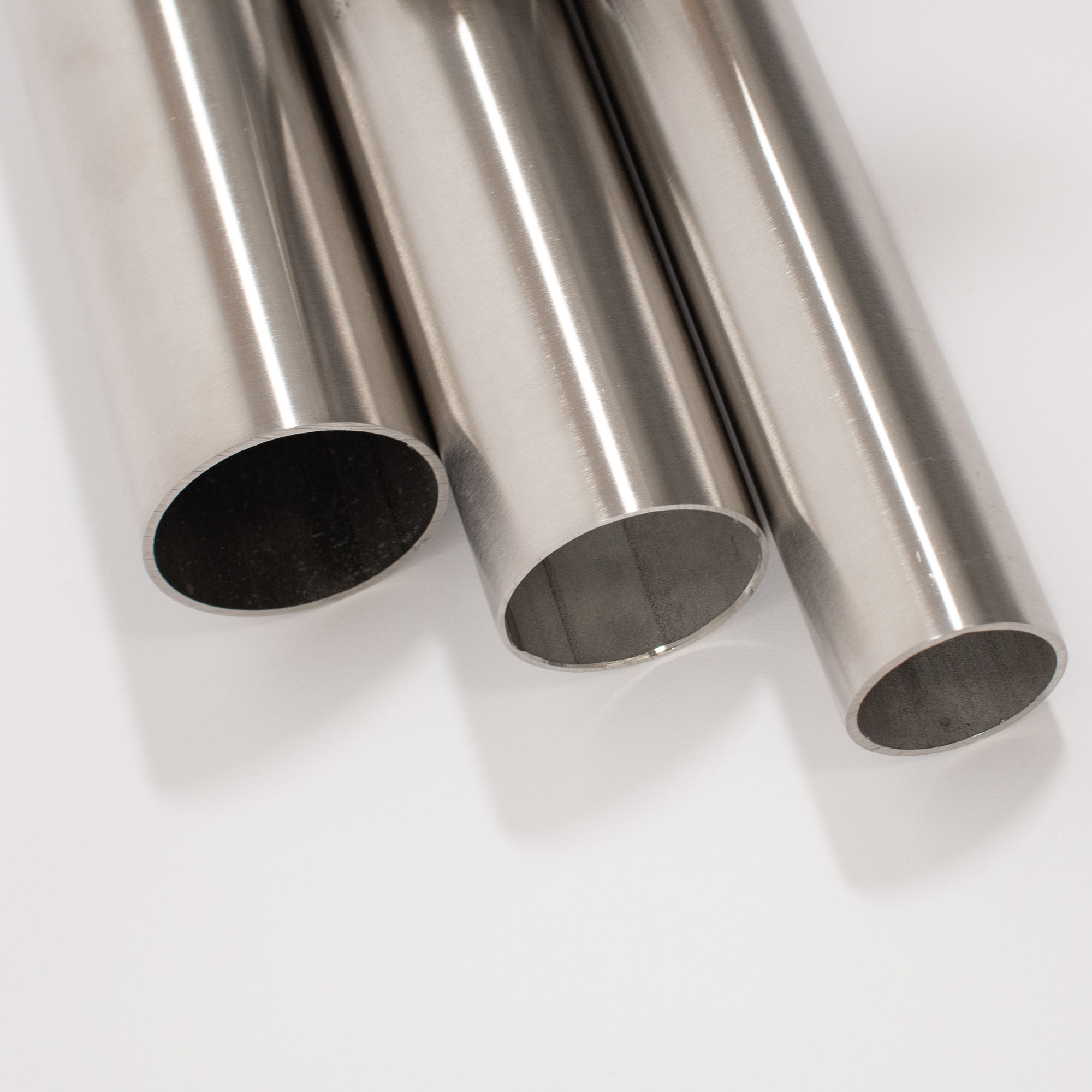 Tubes ronds en acier inoxydable pour mains courantes, trois tubes brossés aux extrémités ouvertes en gros plan, détourés
