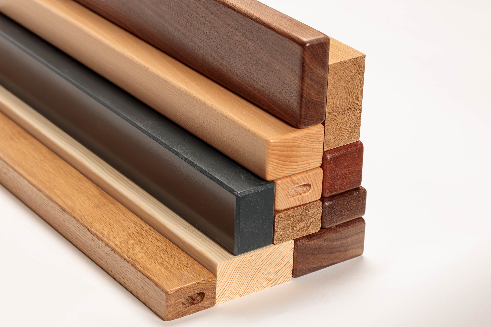 Mains courantes en bois rectangulaires empilées, diverses essences et teintes, profils clairs, foncés et laqués noir