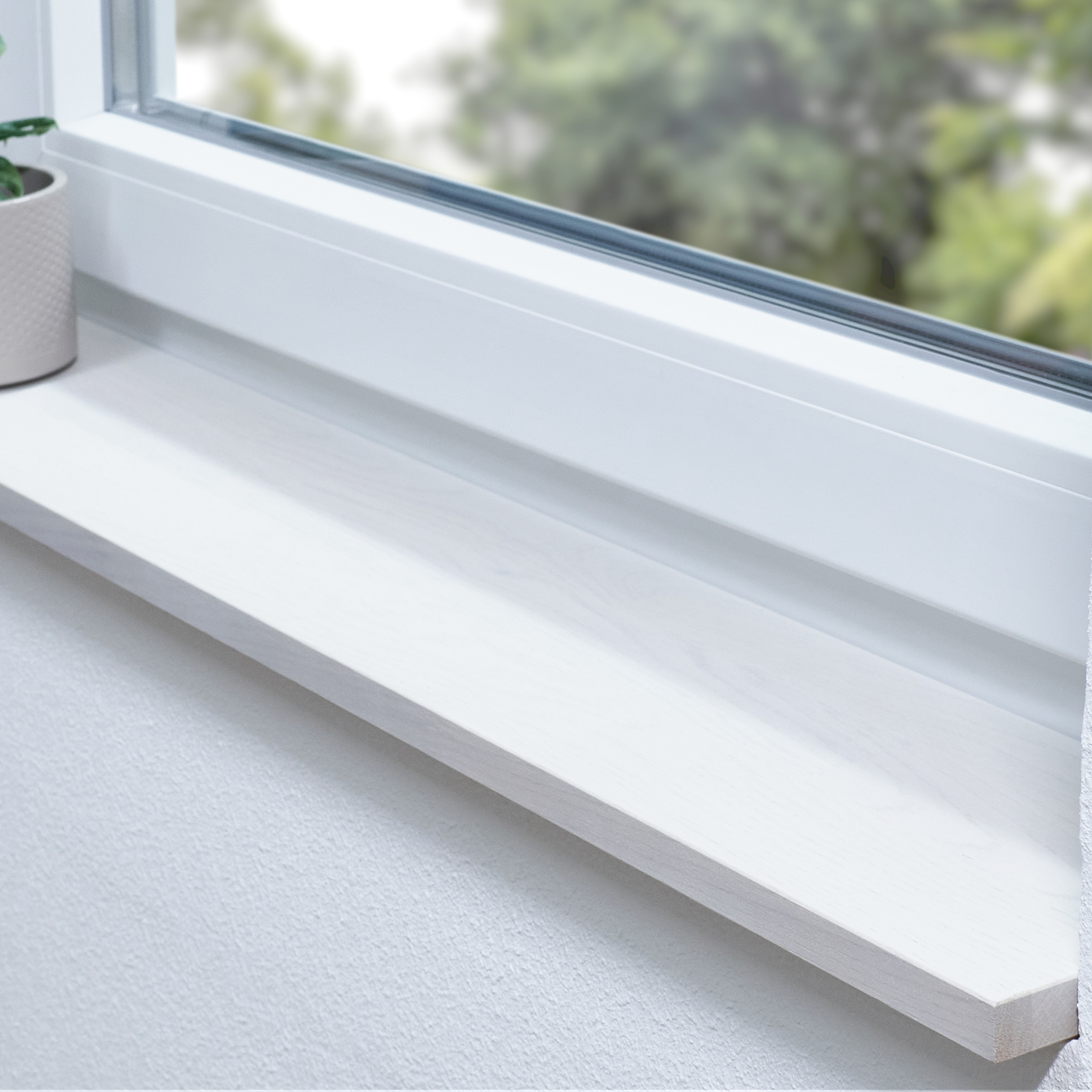 Appui de fenêtre en chêne teinté blanc, abouté, dans une embrasure blanche, plante en pot sur le côté et vue sur la verdure