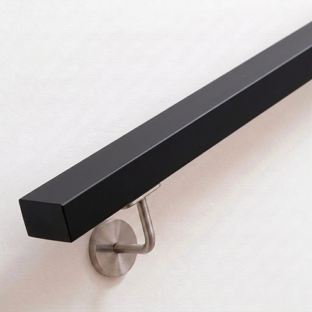 Main courante rectangulaire en hêtre laquée noir avec support inox sur mur blanc, extrémité droite, vue oblique