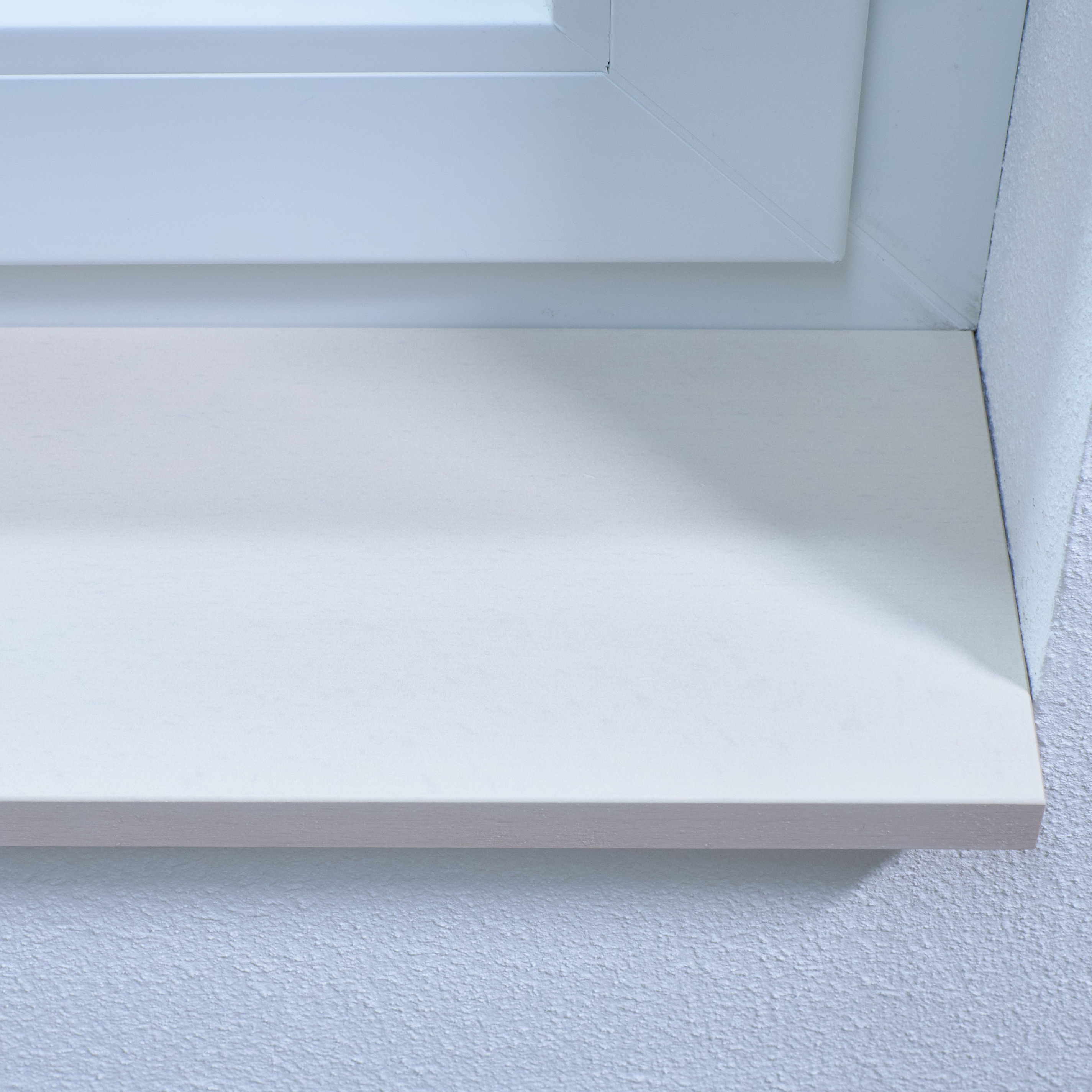 Appui de fenêtre en hêtre teinté blanc, gros plan du chant avant de l'appui blanc contre l'embrasure blanche