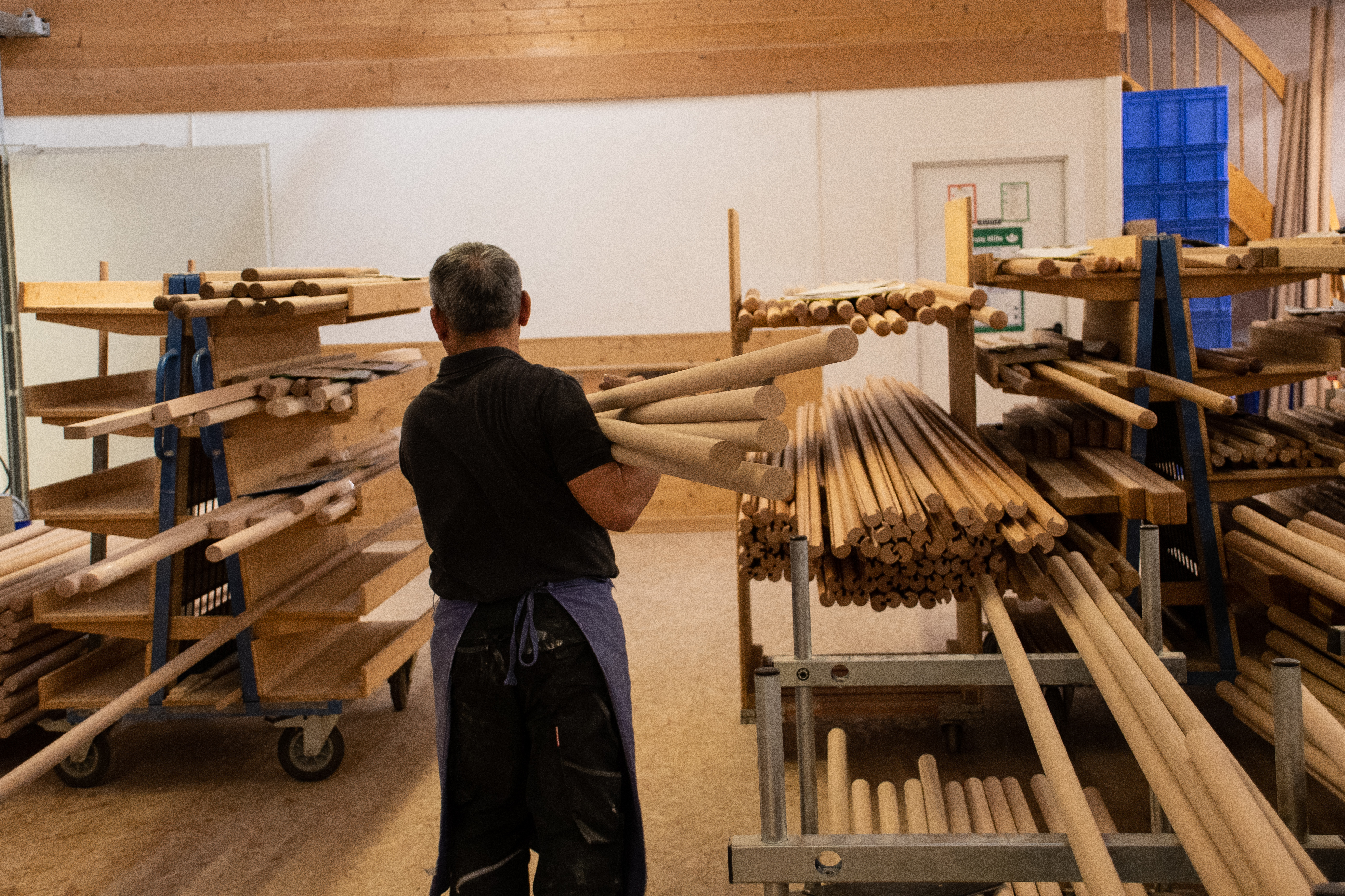 Barres rondes en bois sur l'étagère de l'atelier, un employé trie les barres dans l'atelier de tournage, nombreux diamètres