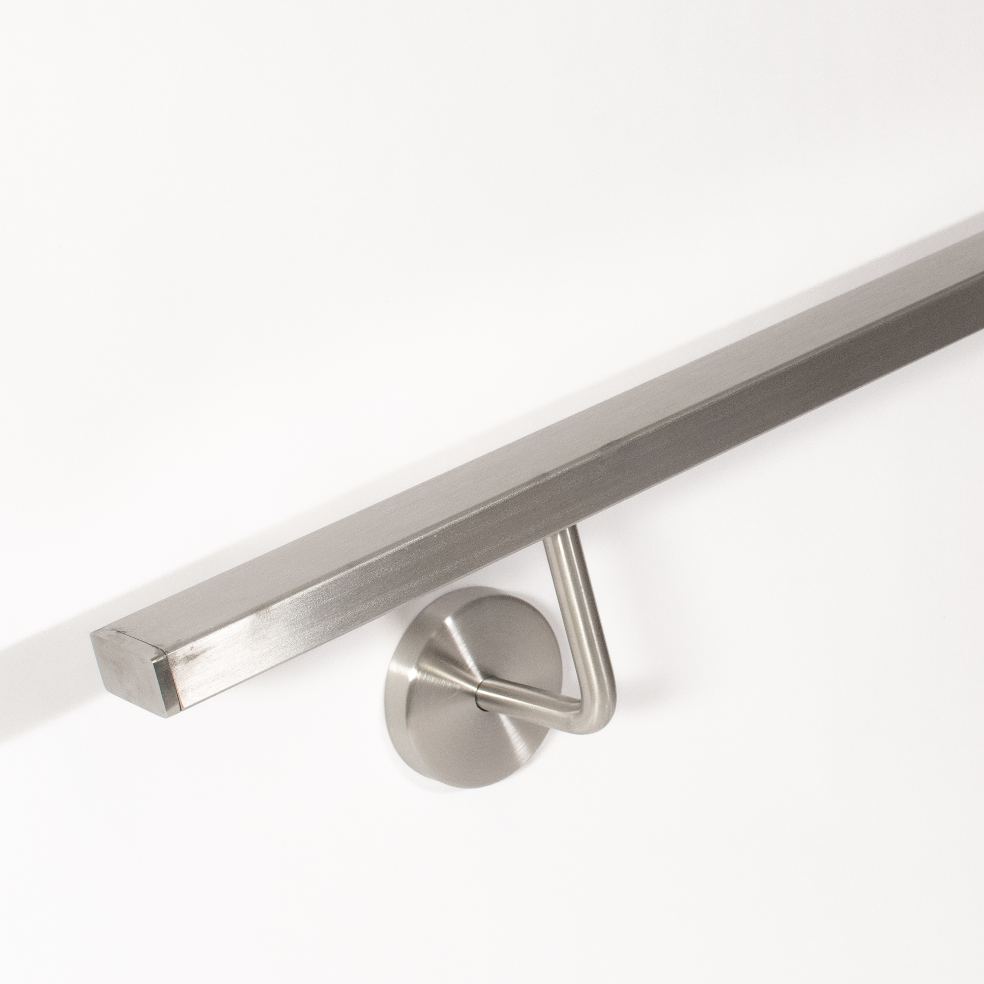 Main courante rectangulaire en acier inoxydable avec support mural inox cintré, vue en contre-plongée, bout sur mur blanc