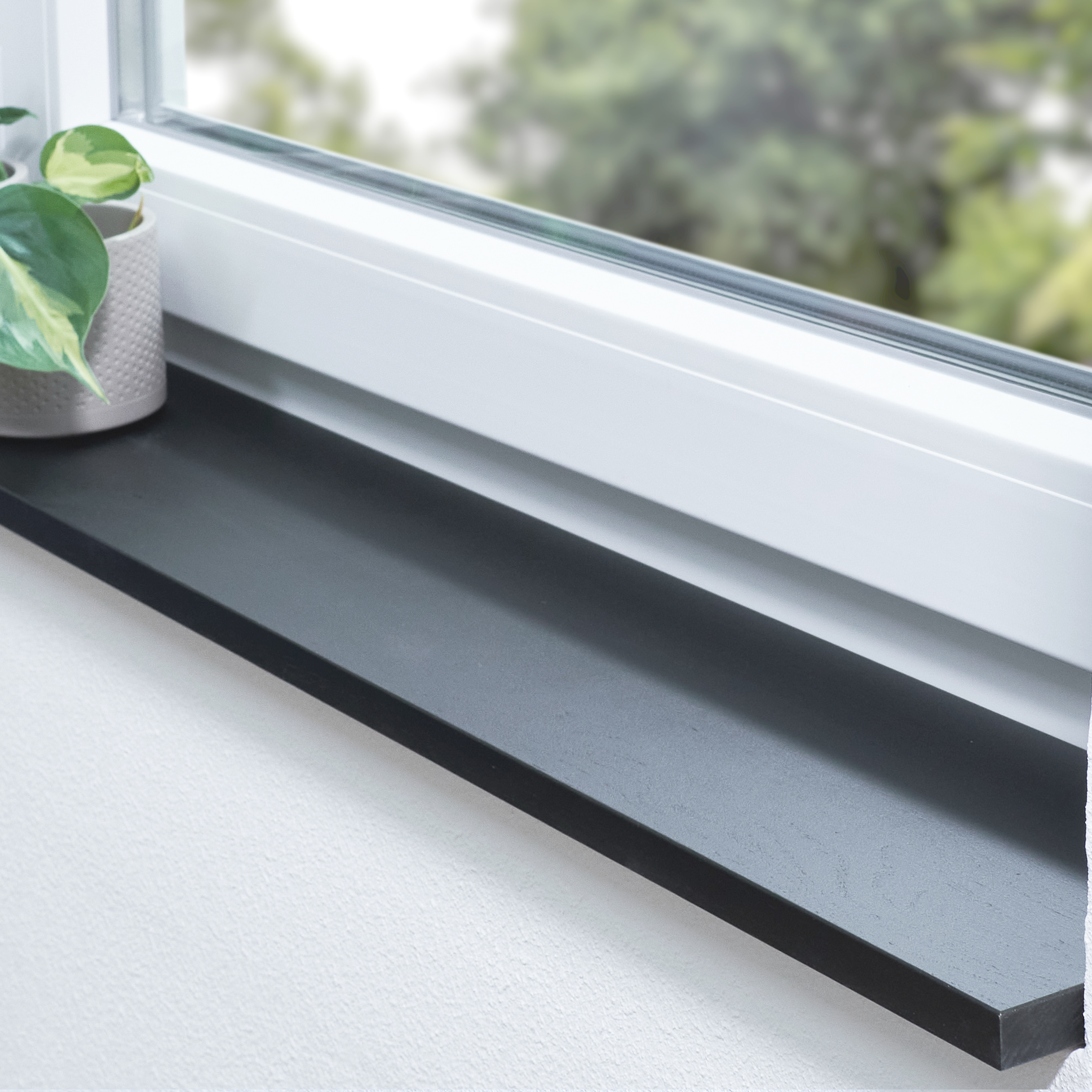 Appui de fenêtre en chêne sauvage teinté noir, abouté, dans une embrasure blanche avec plante et vue sur la verdure