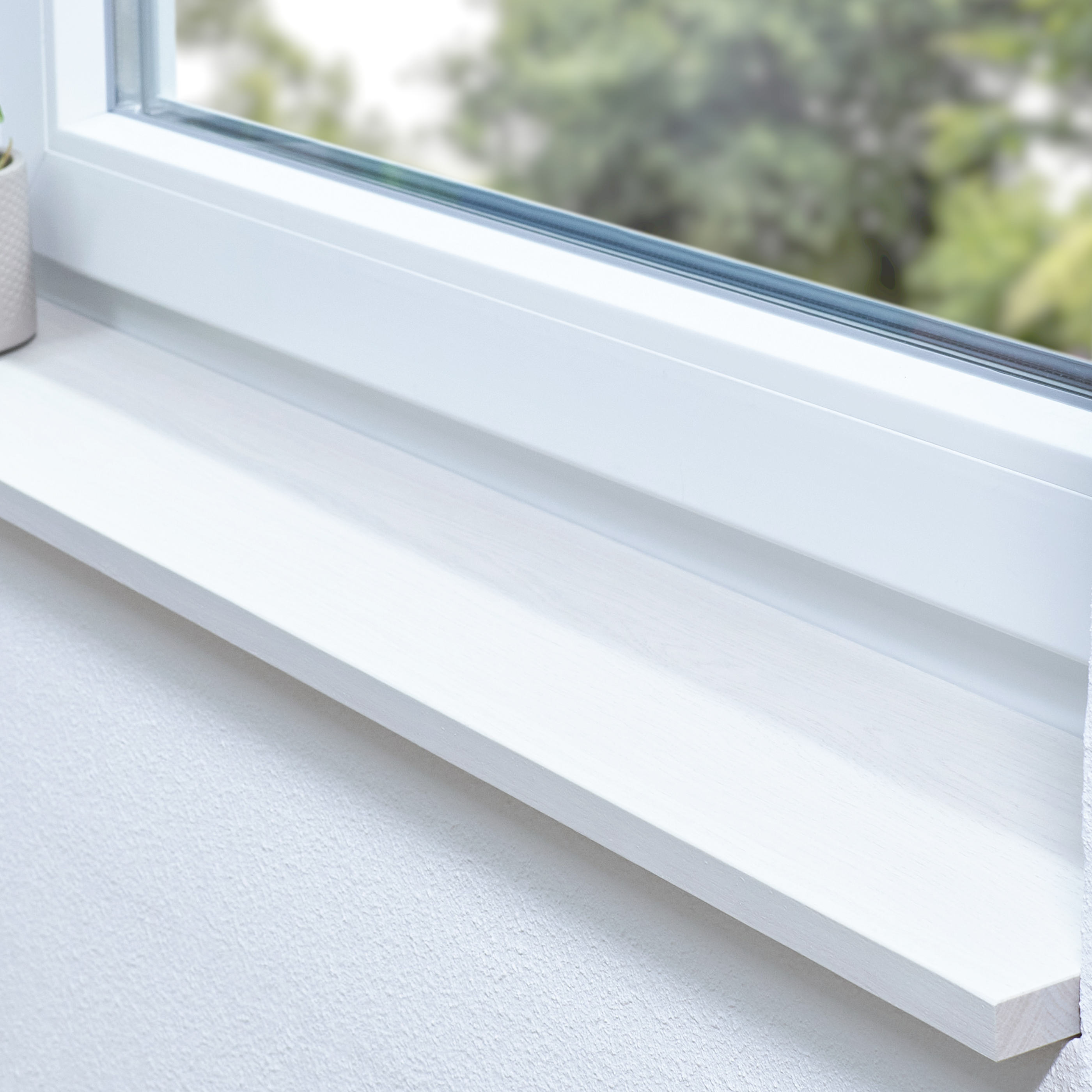 Appui de fenêtre en chêne teinté blanc dans une embrasure blanche, plante en pot sur le côté et vue sur la verdure