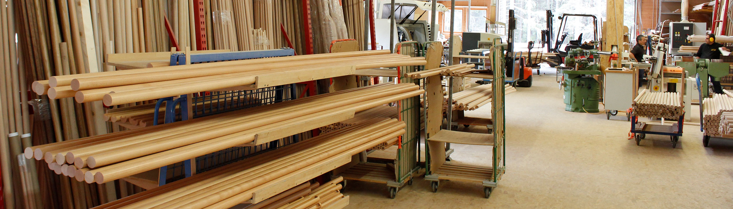 Fabrication de mains courantes : stock de mains courantes en bois clair et barres rondes sur chariots à l'atelier, bannière