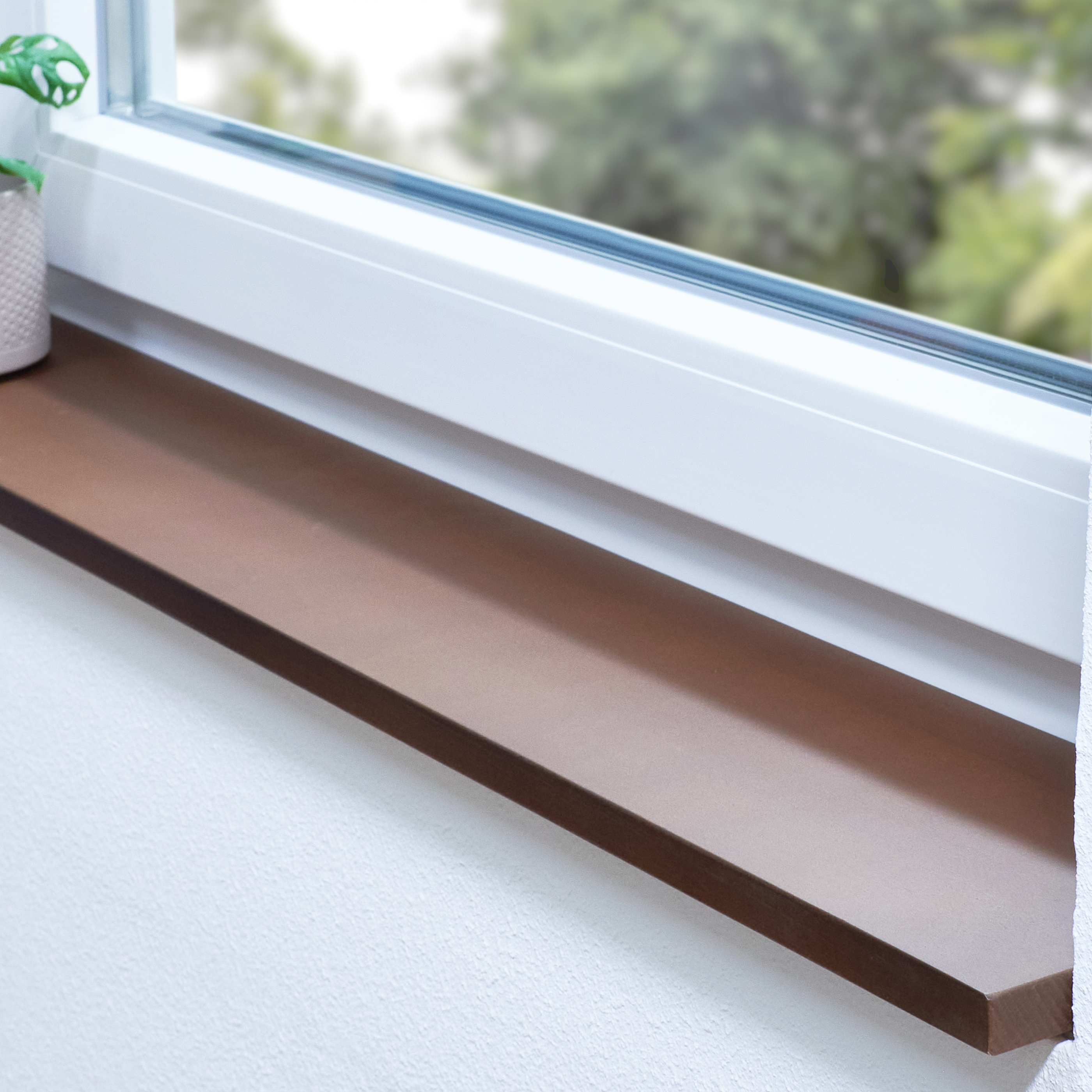 Appui de fenêtre en hêtre teinté brun sur mesure, posé dans une niche devant une fenêtre blanche, vue sur la verdure