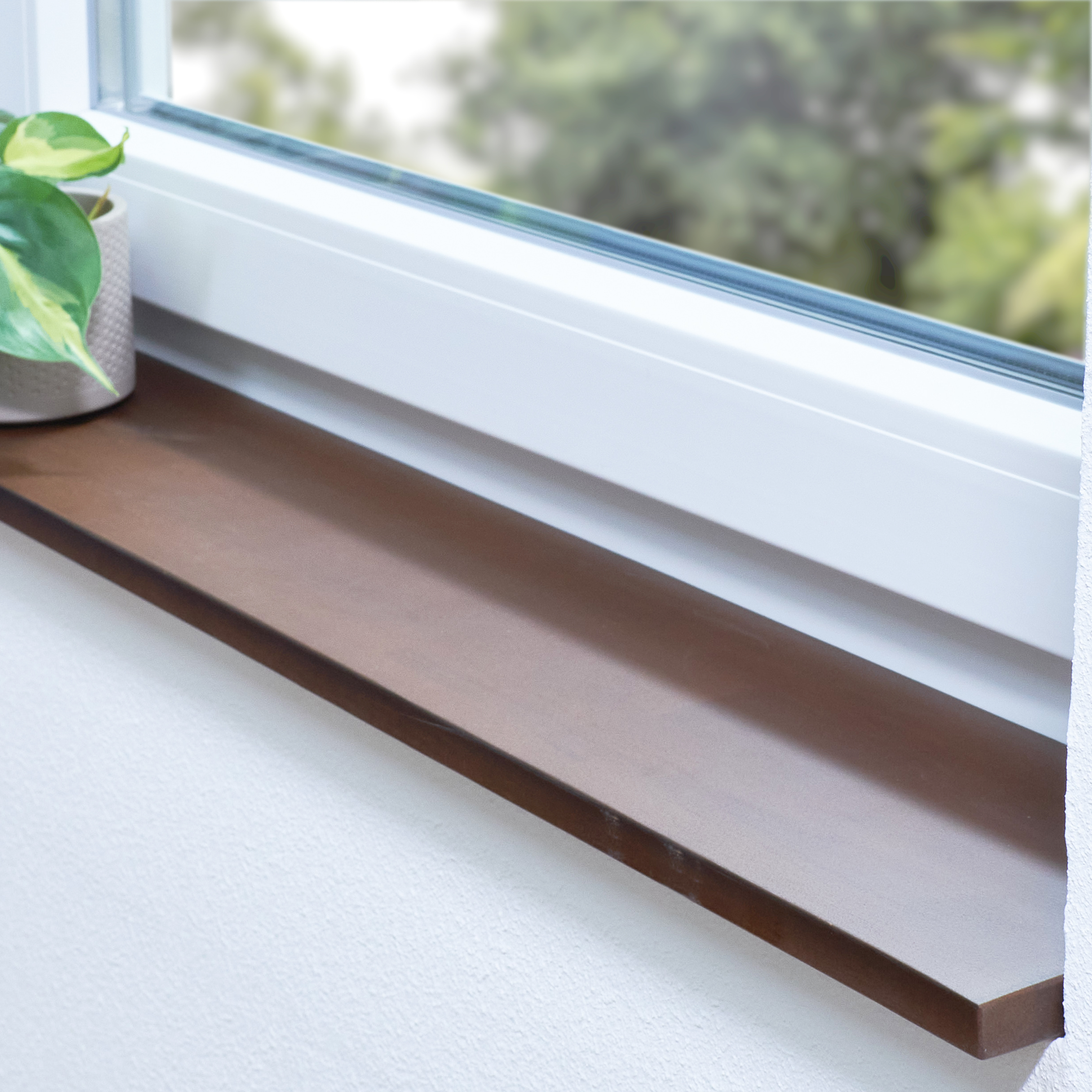 Appui de fenêtre en hêtre à cœur rouge teinté brun, abouté, dans une embrasure blanche avec plante et vue sur la verdure