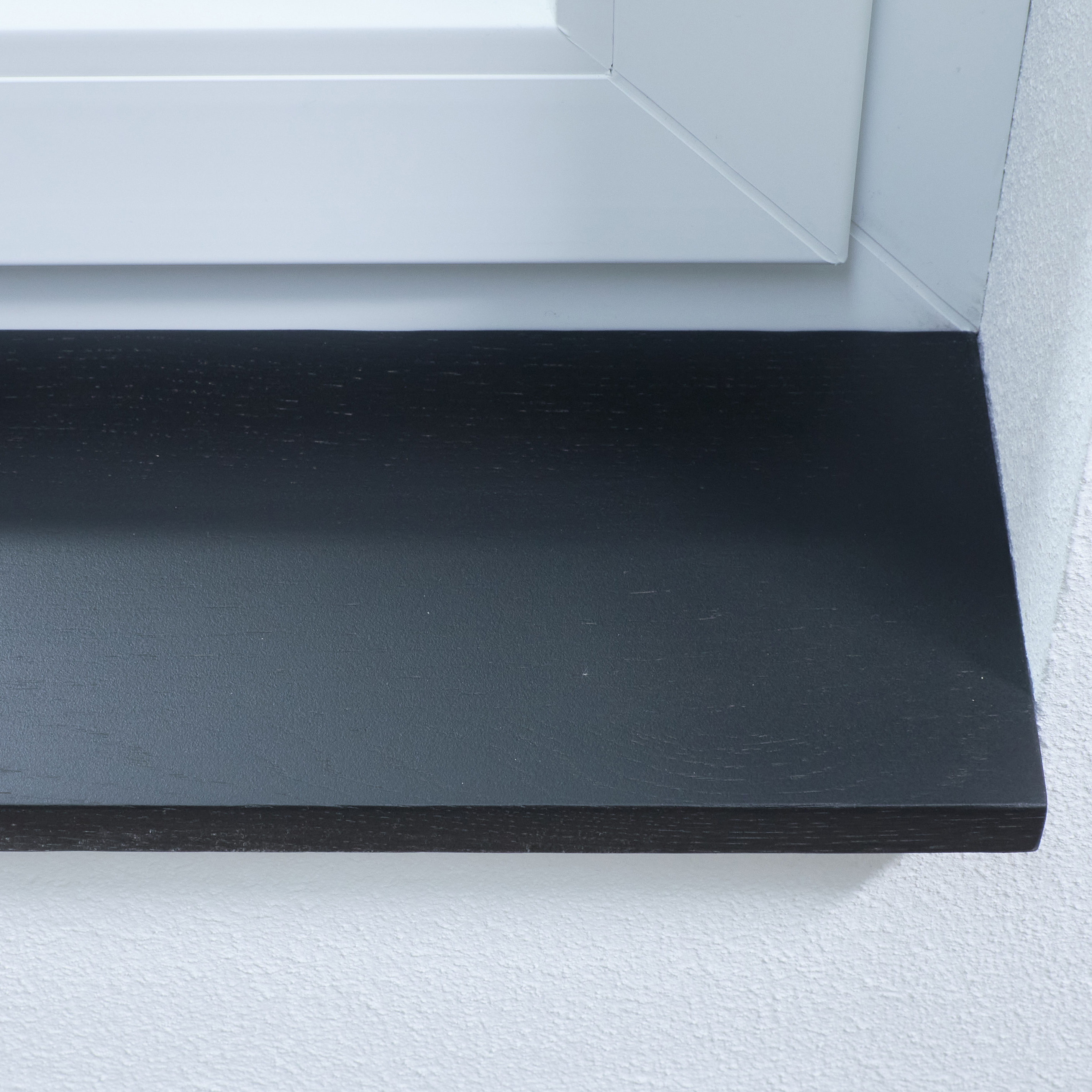 Appui de fenêtre en chêne teinté noir, gros plan du chant avant à légère structure du bois dans une embrasure blanche