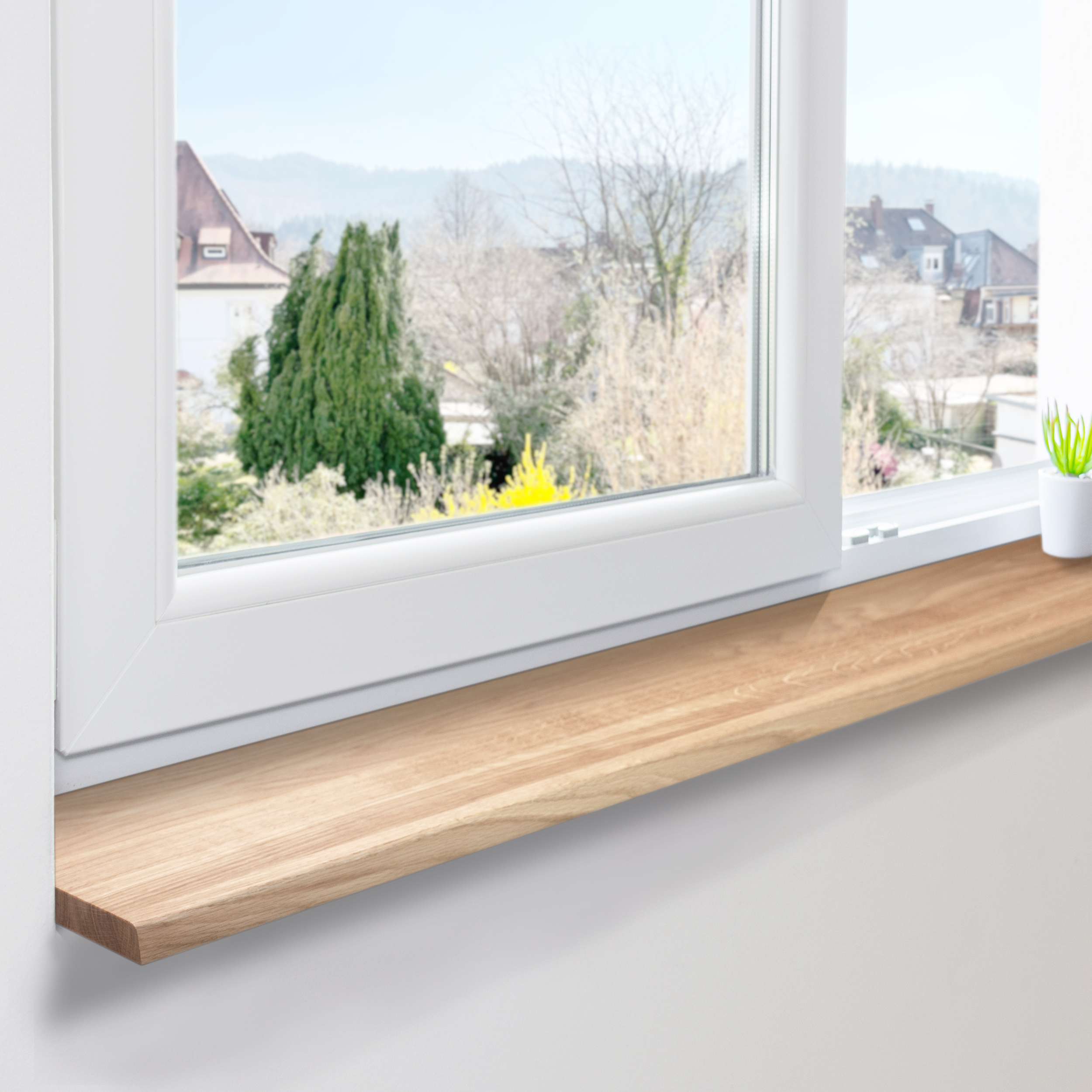 Appui de fenêtre en chêne naturel posé sur fenêtre blanche en PVC, lamelles continues, vue sur maisons et arbres