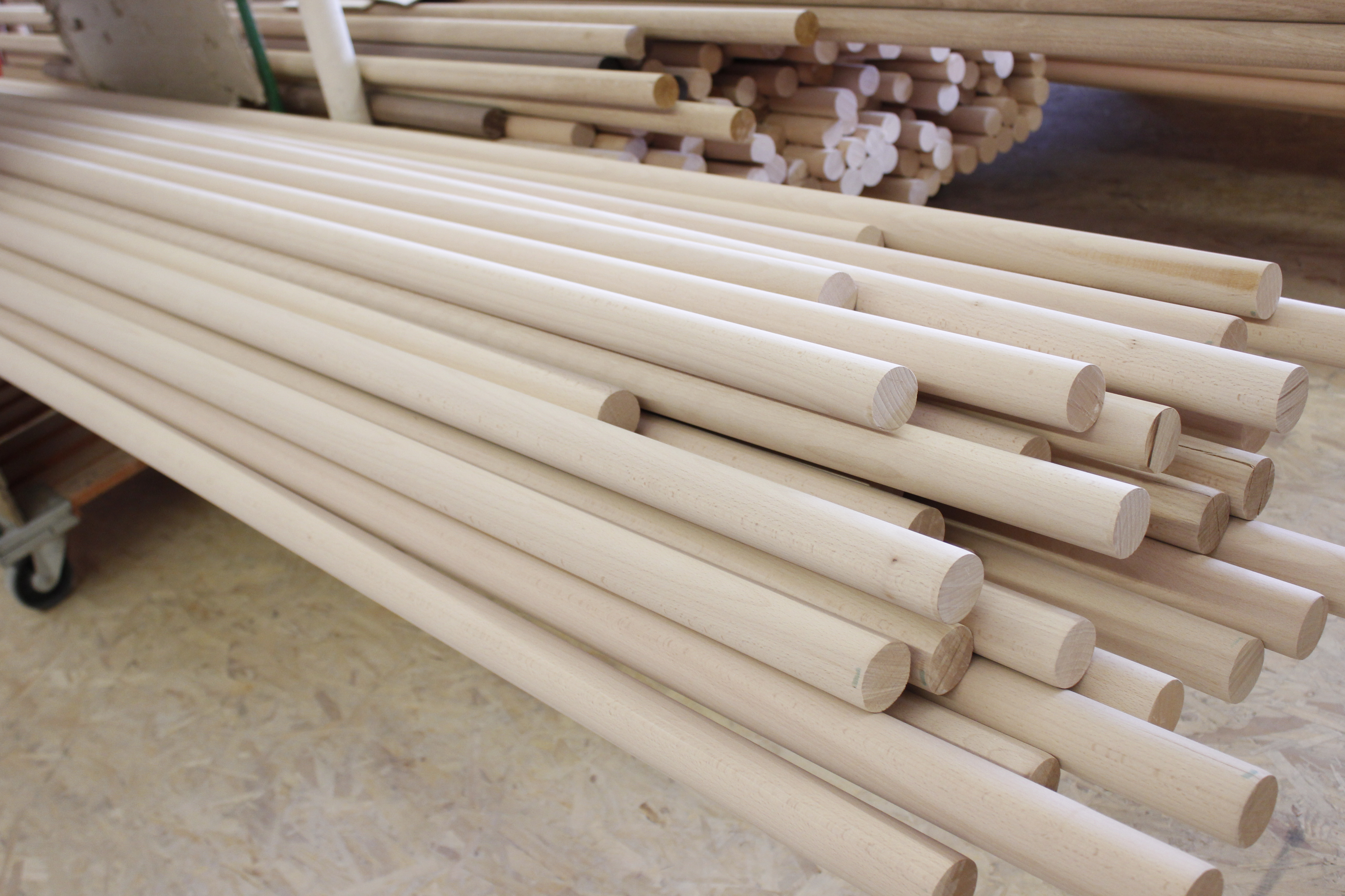 Mains courantes rondes en bois brut empilées sur un chariot à l'atelier, bois clair non traité sans finition de surface