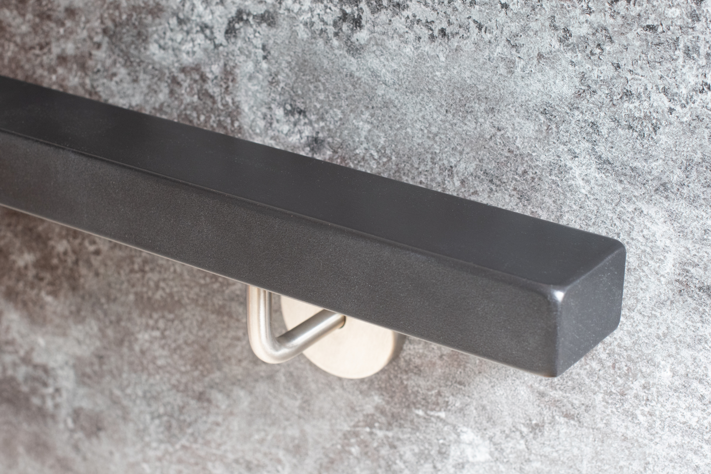 Main courante rectangulaire laquée en gris avec support mural inox sur mur en pierre grise, extrémité droite, vue en biais