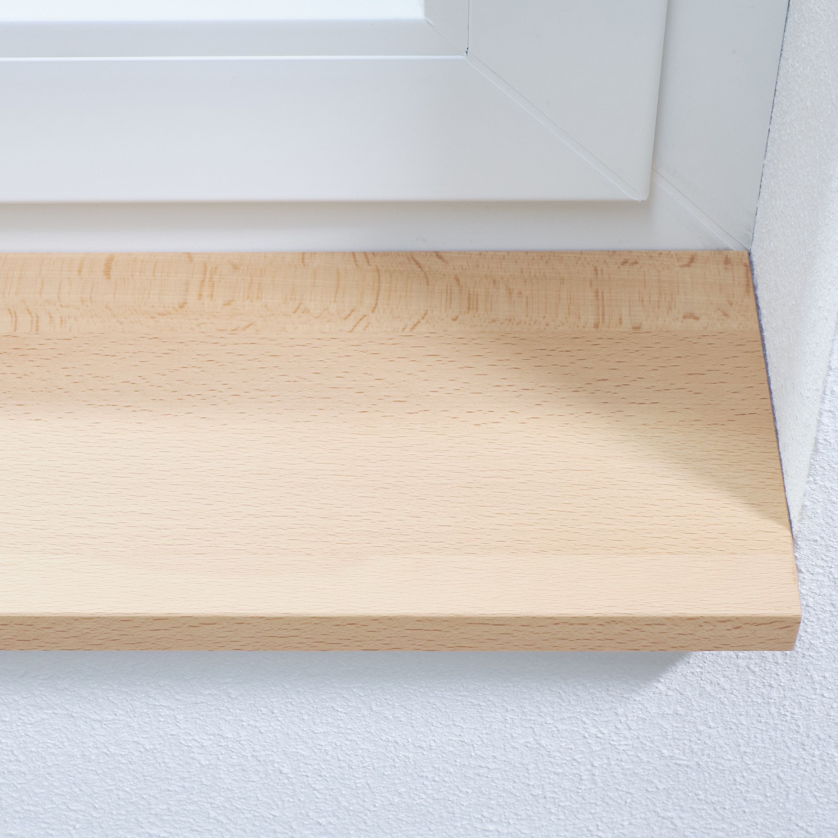 Appui de fenêtre en hêtre naturel, gros plan du chant avant au veinage clair du hêtre, jonction avec l'embrasure blanche