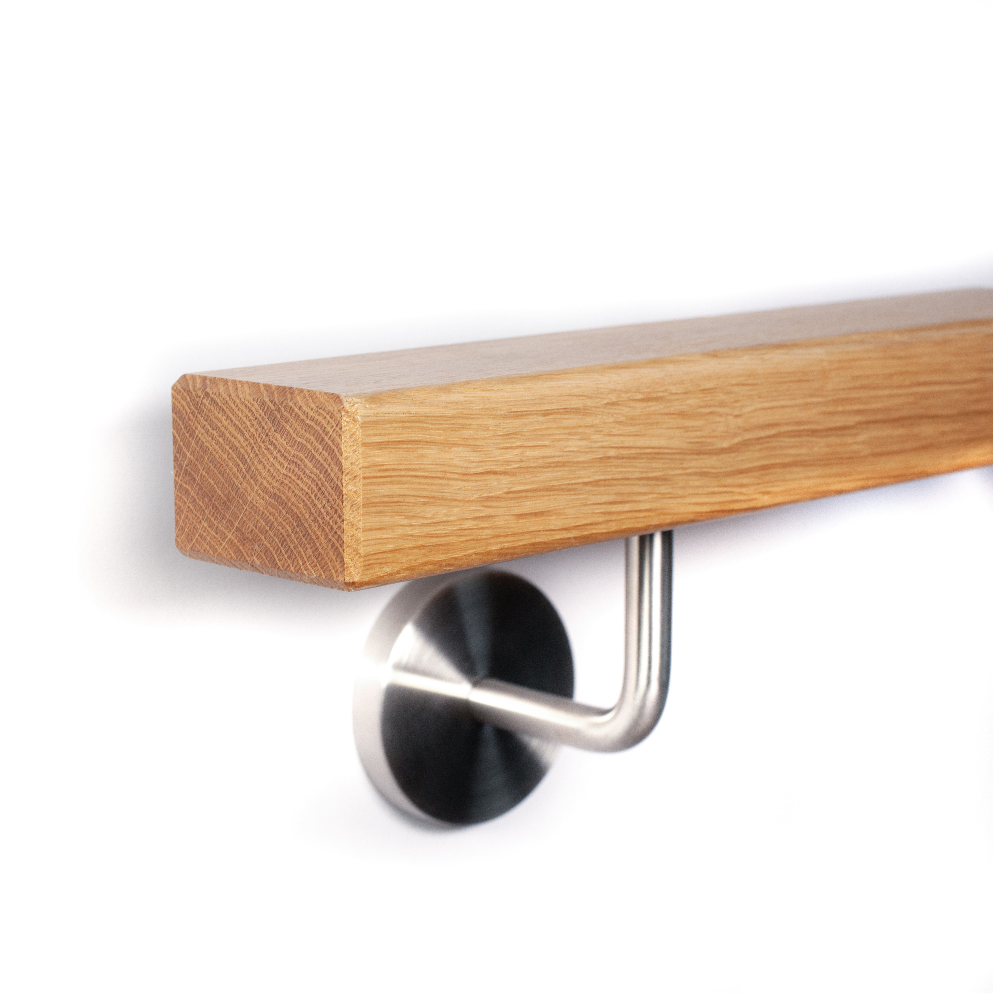 Main courante rectangulaire en chêne avec chanfrein et support mural inox à rosace sur mur blanc, gros plan en contre-plongée